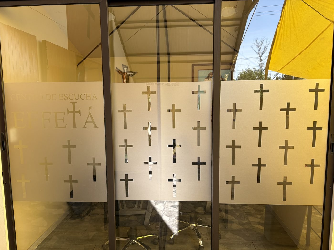Puerta de cristal del Centro de Escucha Effetá, con cruces grabadas