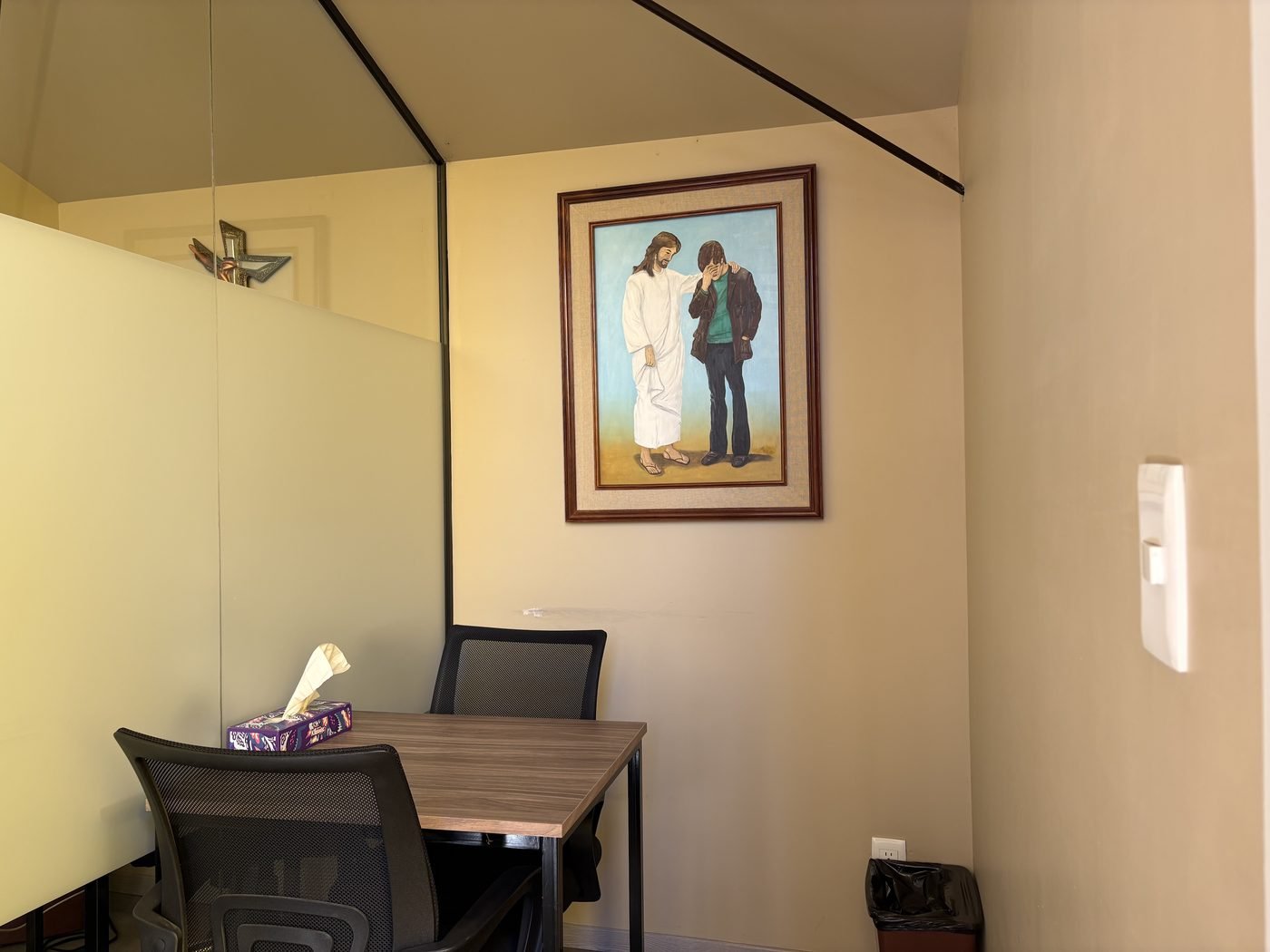Interior del Centro de Escucha: mesa, sillas y un cuadro de Jesús con un joven